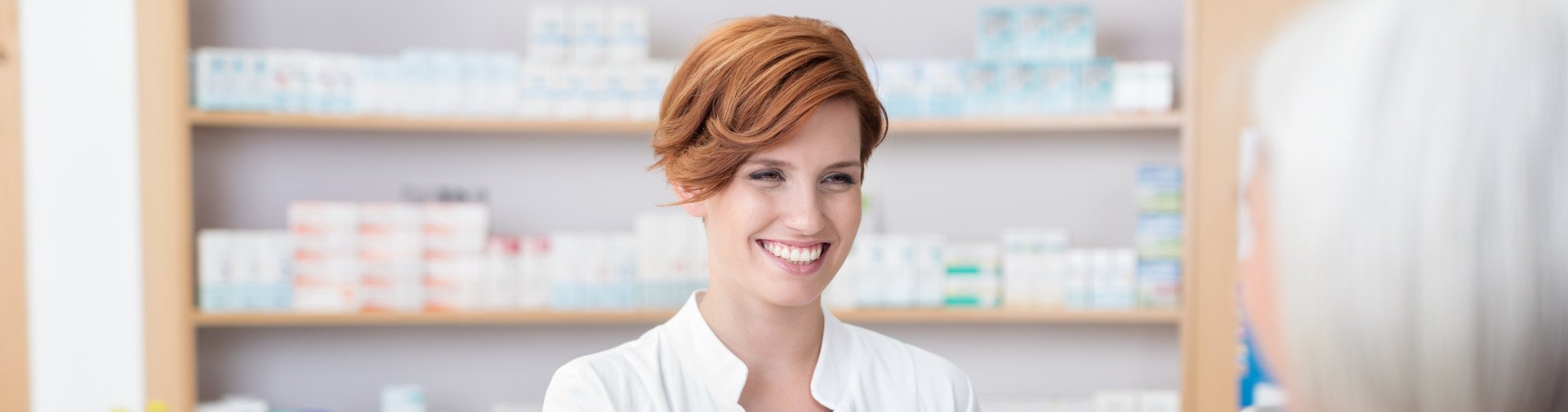 AdobeStock_91567936.jpeg Eine Apothekerin, die einem Kunden ein Medikament überreicht